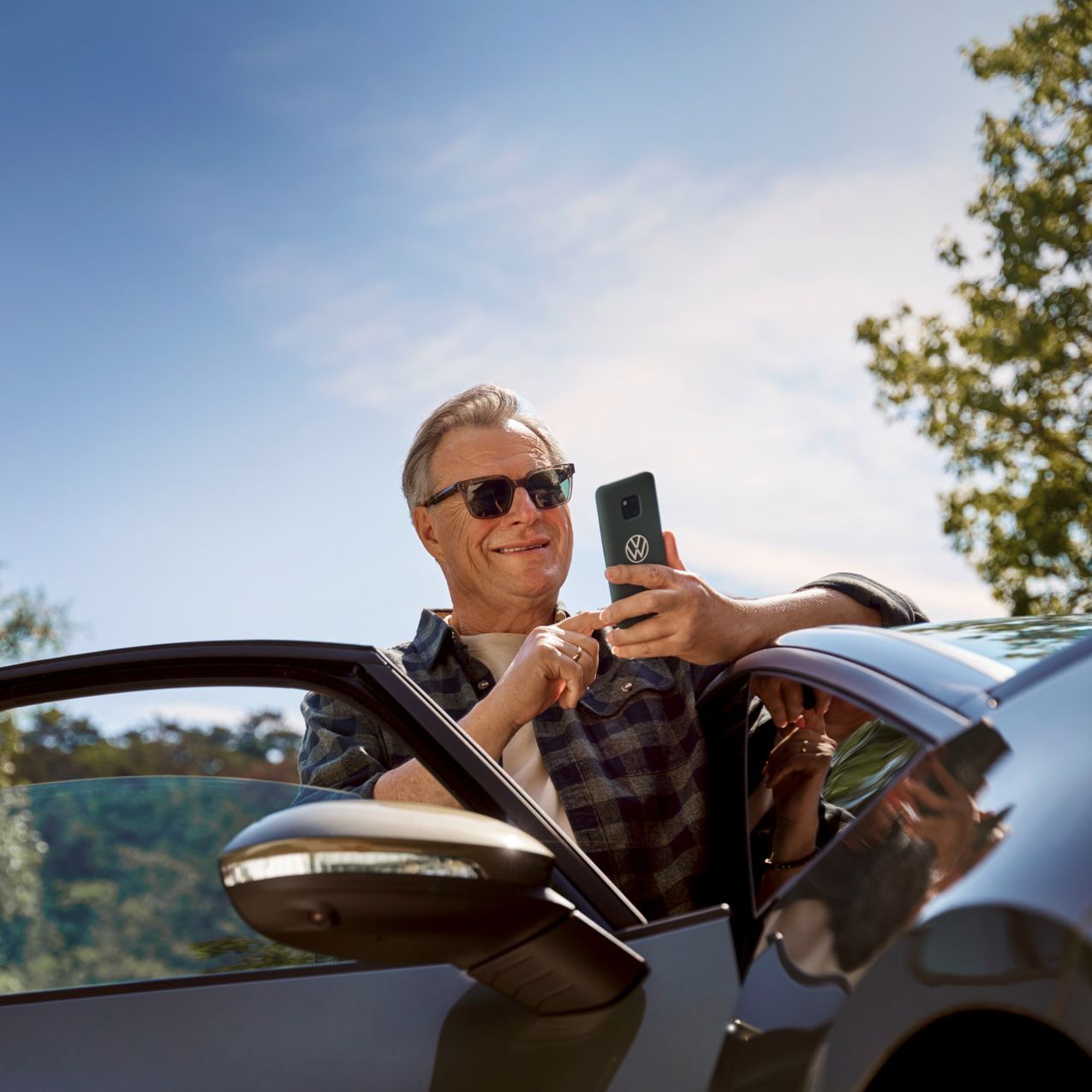  Ein Mann mit einem Smartphone stehen neben seinem ID.3