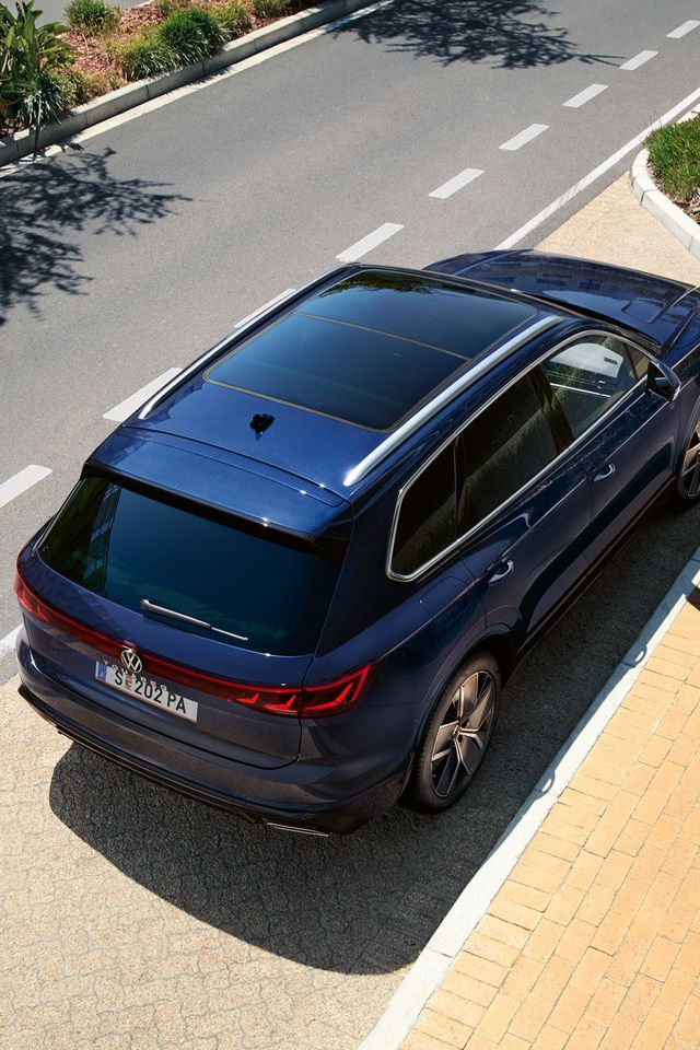 Ein VW Touareg R-Line parkt am Straßenrand, Ansicht von schräg oben auf das Heck und Panoramaglasdach.