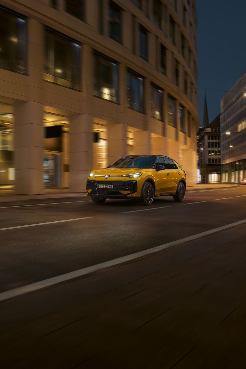 Ein gelber VW T-Roc R-Line fährt nachts durch eine urbane Umgebung.