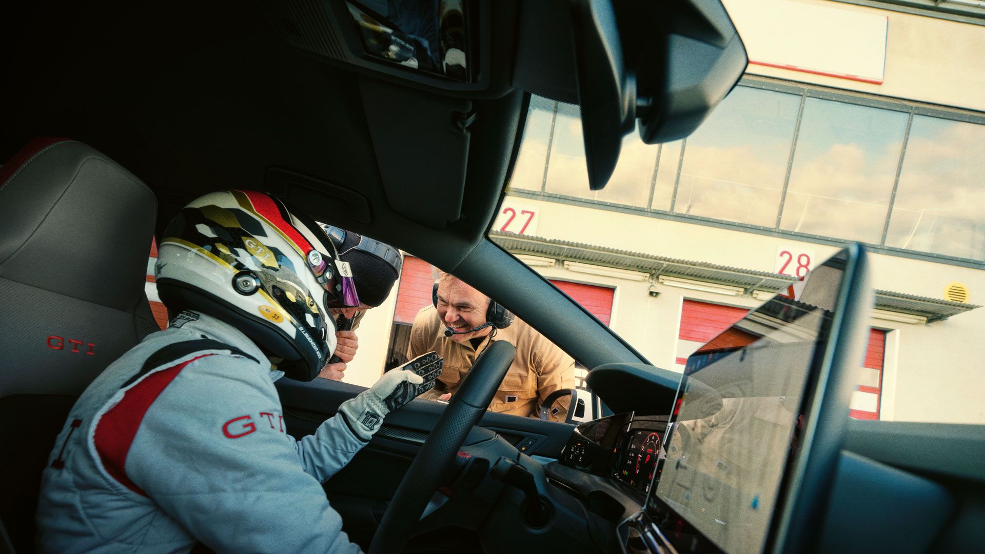 Rennfahrer sitzt im VW Golf GTI Clubsport und redet durch das geöffnete Fenster mit einem Mann.