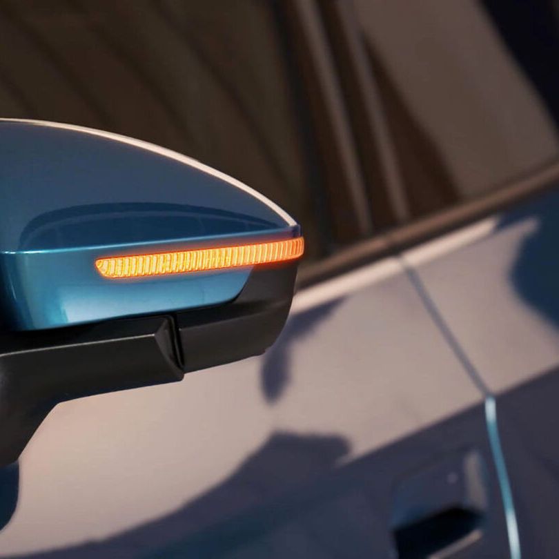 Der Seitenspiegel eines blauen ID.4 mit aktiviertem Warnblinker.