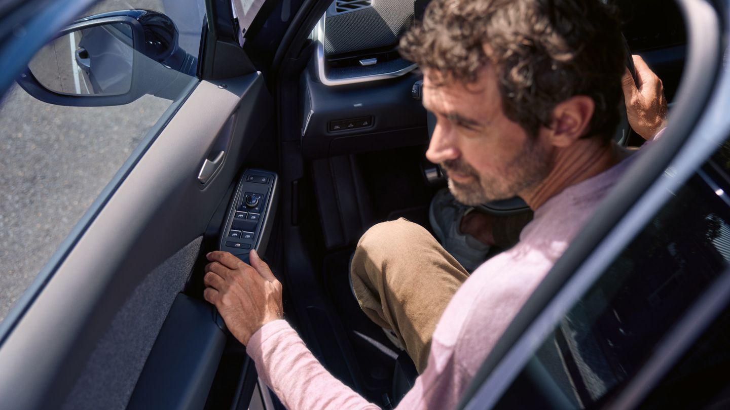 Ein Mann in einem VW ID.3 Neo. Die Fahrertür mit ihren vier Fenterhebern ist halb geöffnet.