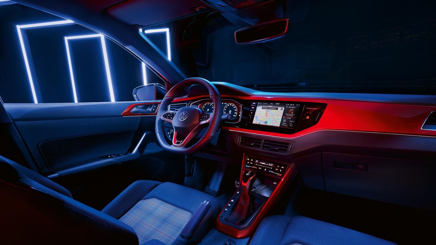 Innenraum eines weißen VW Polo GTI mit Blick vom Beifahrersitz auf Infotainment-Display mit Navigationskarte.