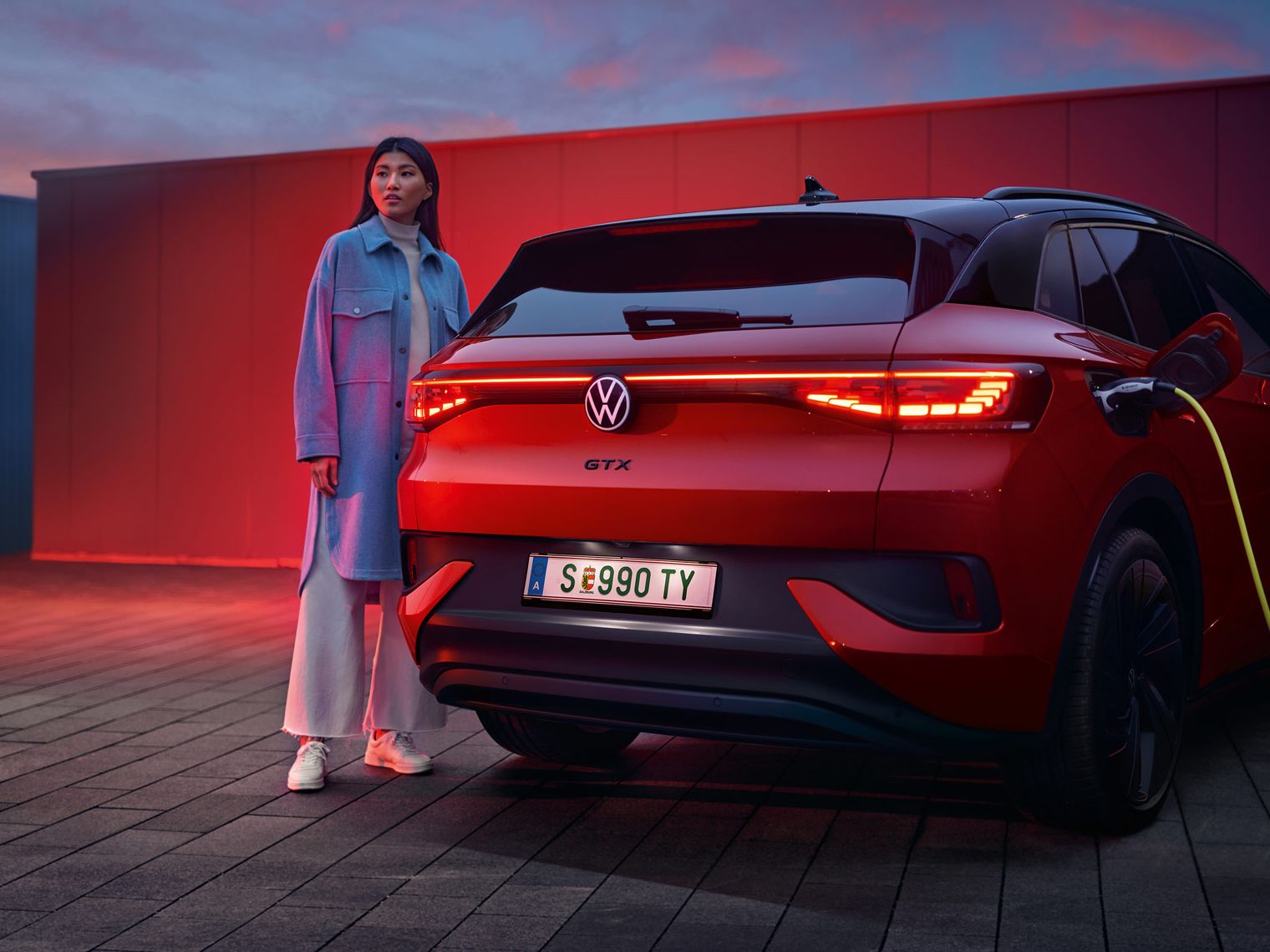 Heckansicht des VW ID.4 GTX 4MOTION, eine Frau steht daneben