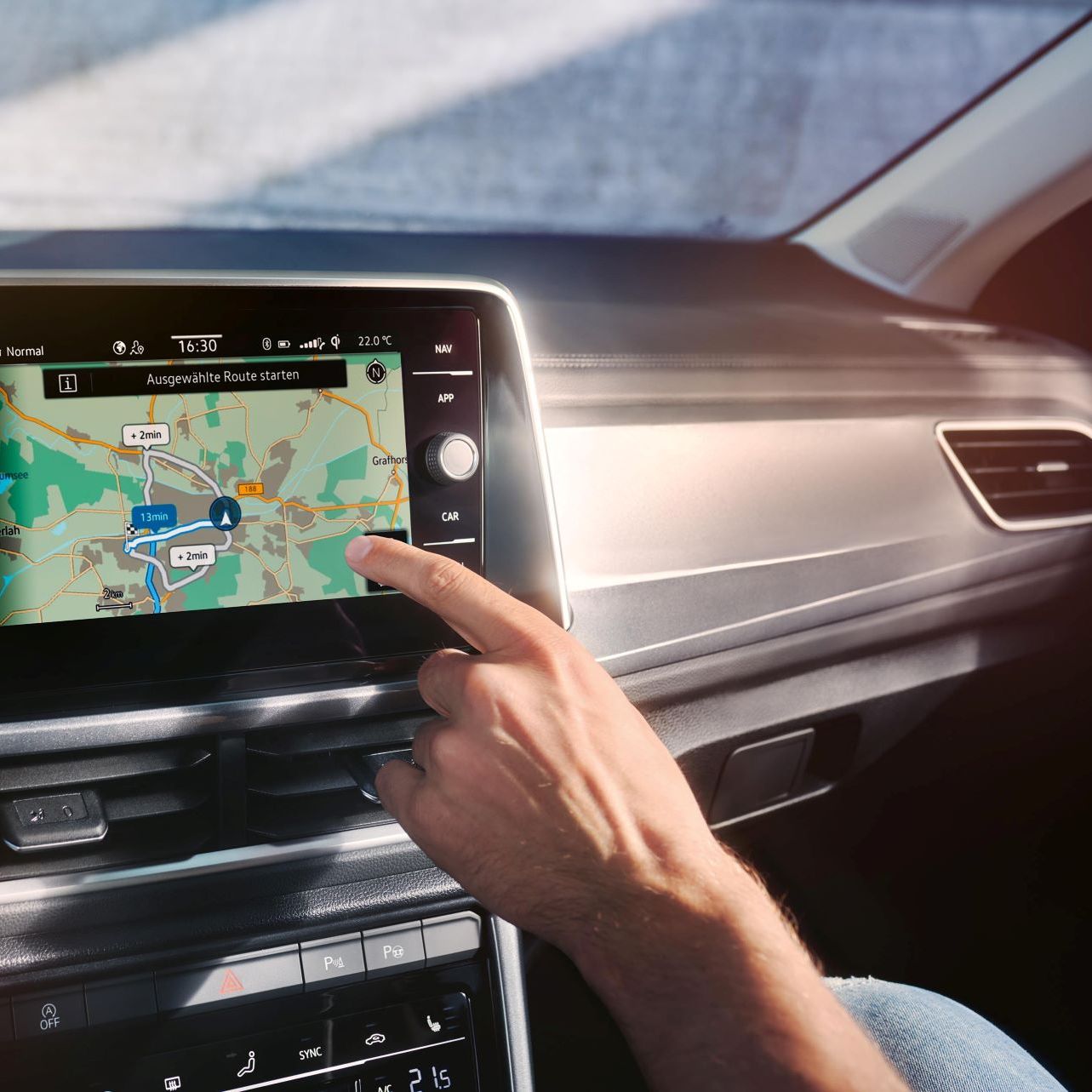 Interieur vom T-Roc mit Fokus auf Infotainment und Person die mit Finger darauf zieg