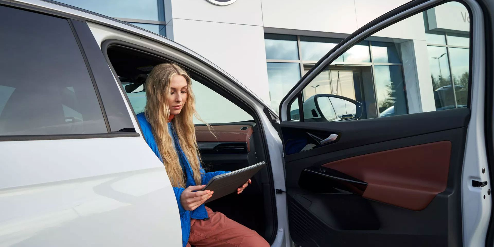 Eine Frau sitzt bei geöffneter Autotüre in einem VW ID.