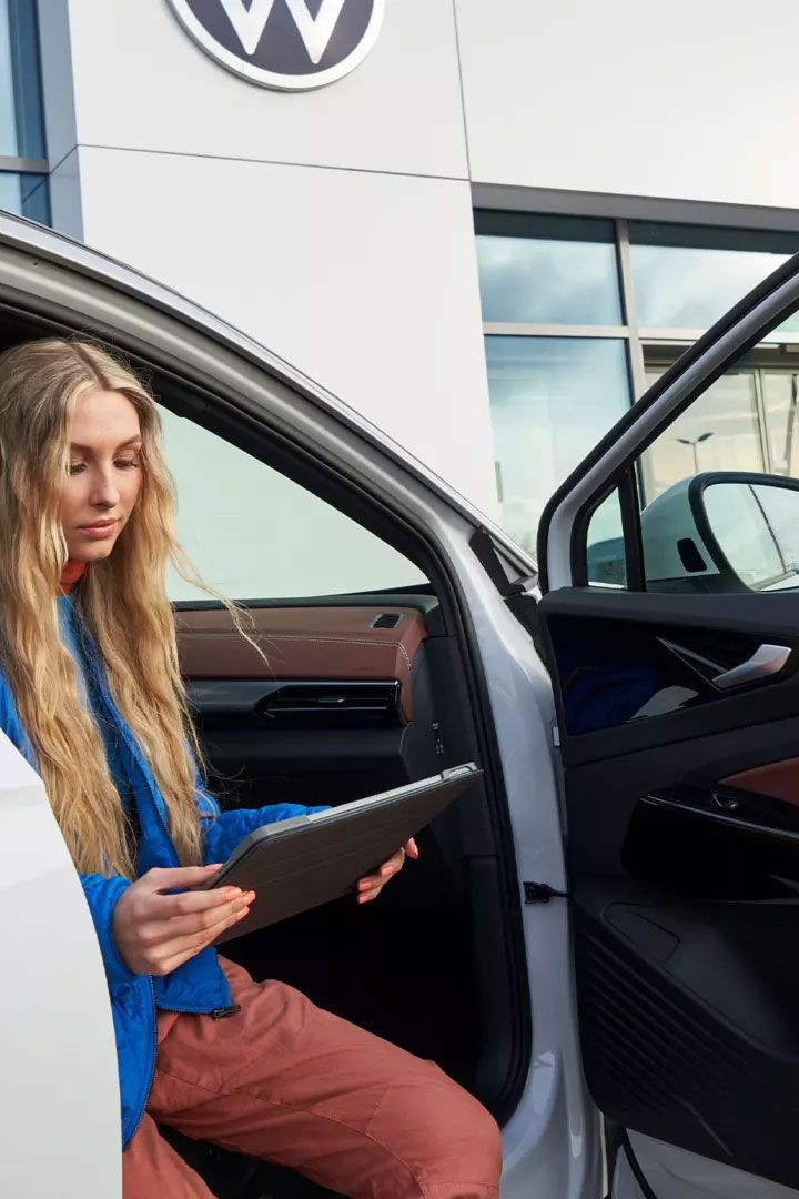 Eine Frau sitzt bei geöffneter Autotüre in einem VW ID.