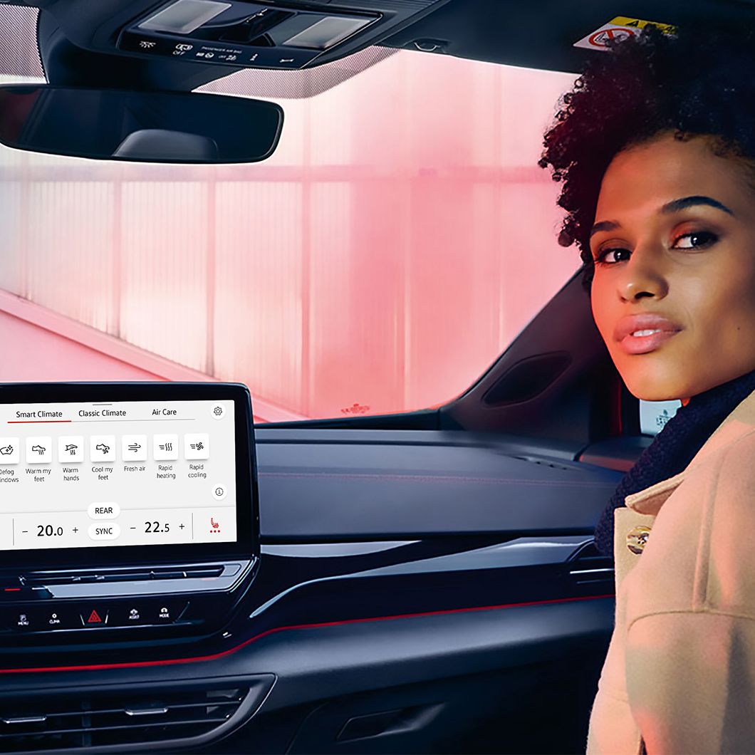 Junge Frau auf der Beifahrerseite des VW ID.4 GTX schaut den Betrachter an