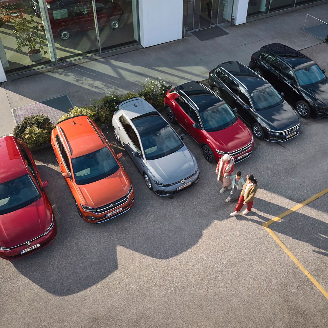 Eine Familie geht neben sechs Vorgängermodellen an einem Autohaus vorbei
