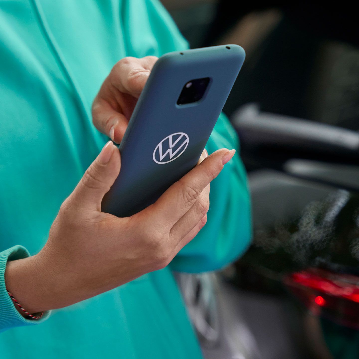 Eine Frau tippt in ihr Smartphone. Auf der blauen Schutzhülle ist das Volkswagen Logo abgebildet.