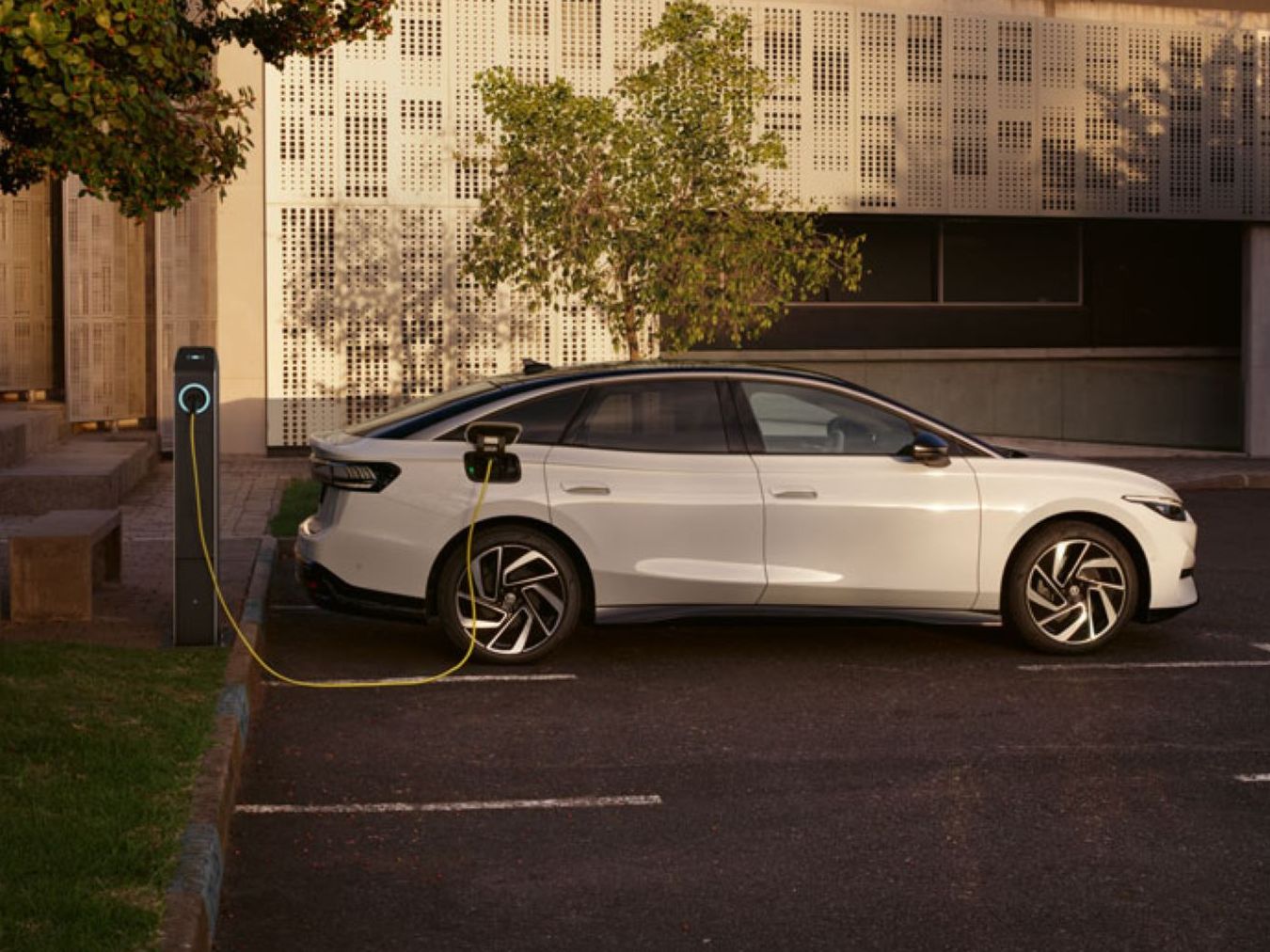 Ein weißer ID. 7 parkt neben einer Ladesäule und wird aufgeladen. 