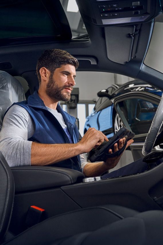 Ein Volkswagen Techniker mit Prüfgerät sitzt in einem Volkswagen Touareg