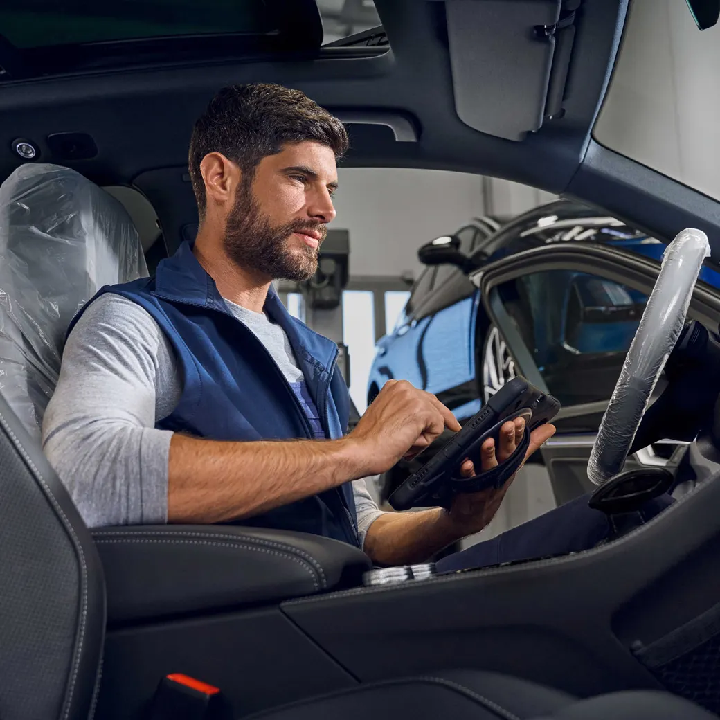 Ein Volkswagen Techniker mit Prüfgerät sitzt in einem Volkswagen Touareg