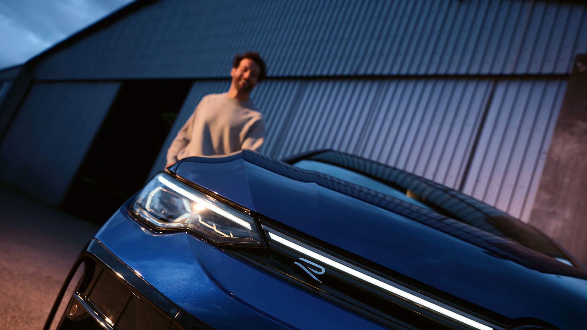 Golf R im Detailshot von der Vorderseite in schräger Ansicht mit Mann im Hintergrund.