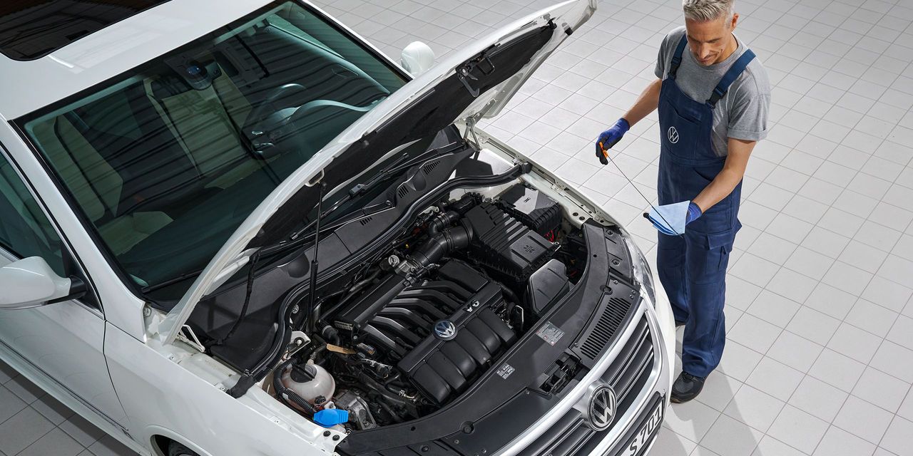 Ein Volkswagen Mechaniker wechselt Öl bei einem weißen Volkswagen Passat.