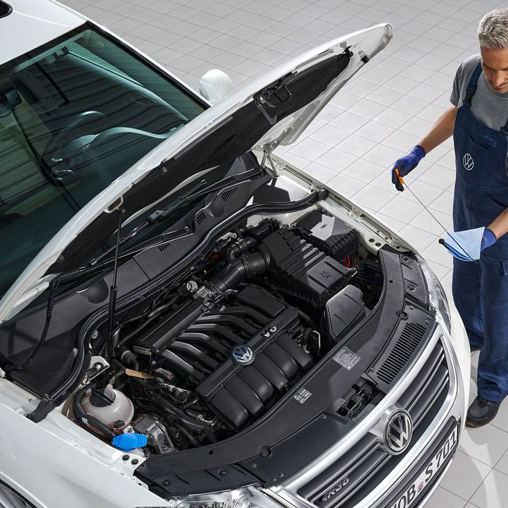 Ein Volkswagen Mechaniker wechselt Öl bei einem weißen Volkswagen Passat.