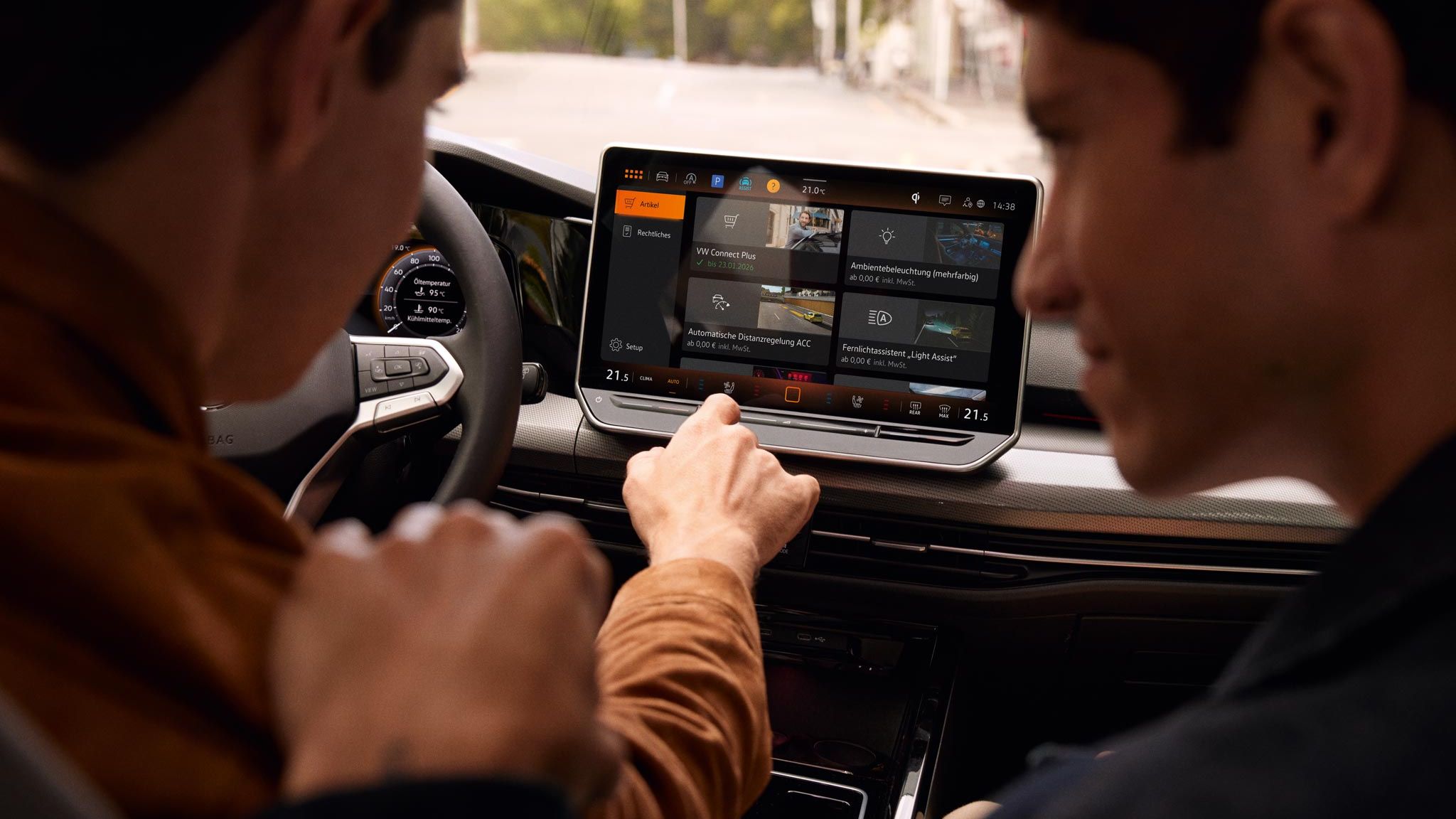 Zwei Männer sitzen im VW Golf und schauen auf das Infotainmentsystem 