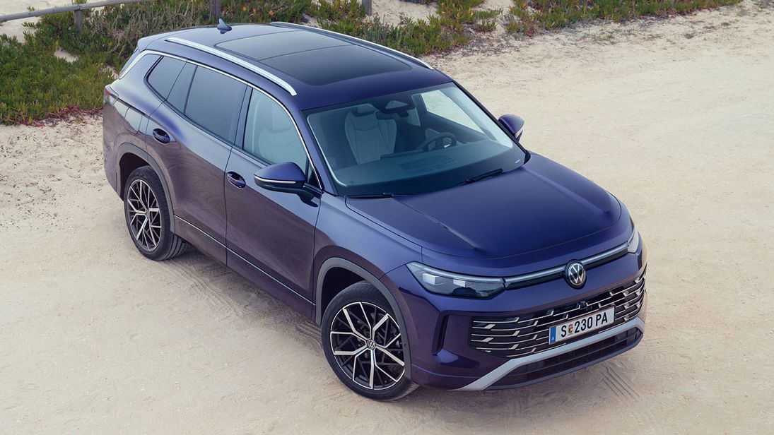 VW Tayron von schräg oben auf einem Parkplatz mit Blick über die Dünen zu Strand und Meer.