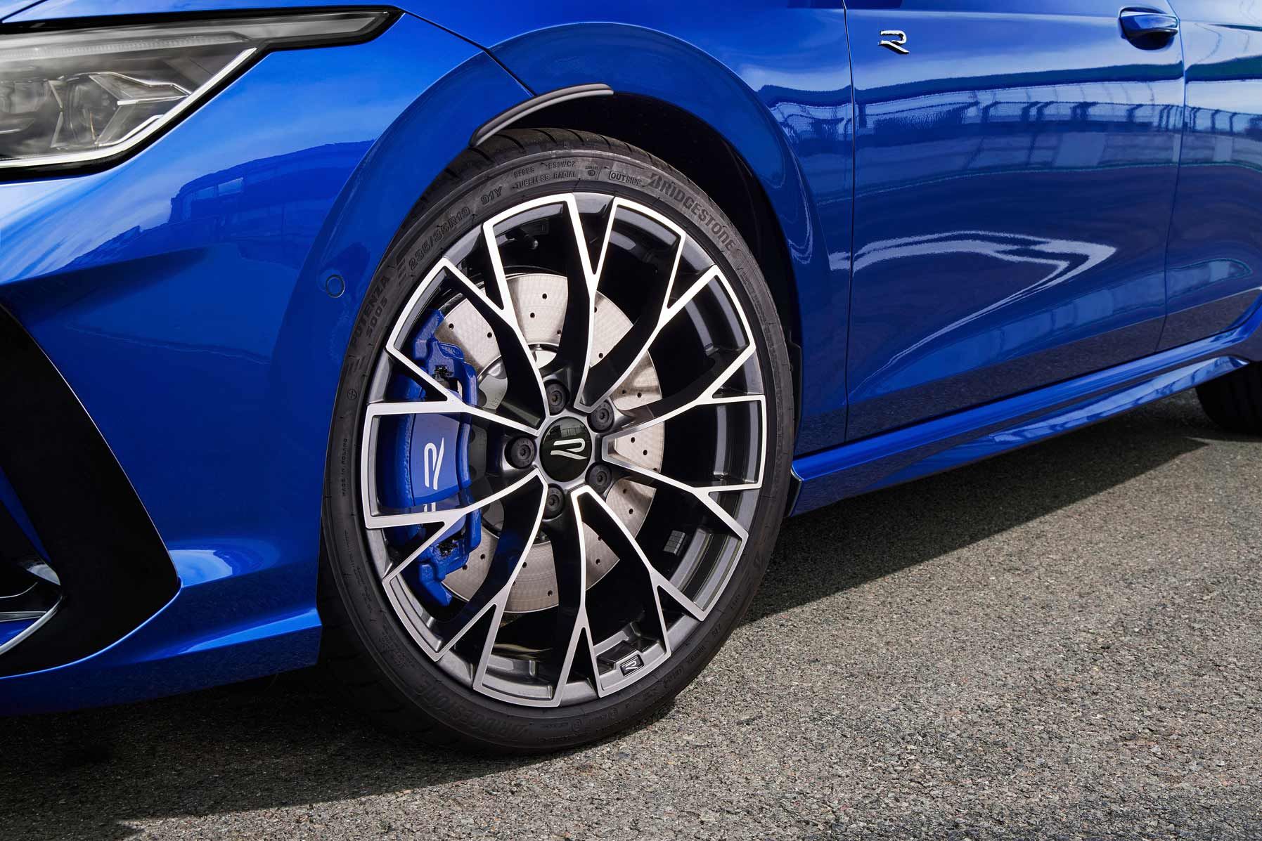 Nahaufnahme eines Volkswagen R mit stilisierten, schwarzen und silbernen Felgen. Die Bremsscheiben sind groß und gut sichtbar. Das Auto steht auf einer Asphaltstraße.