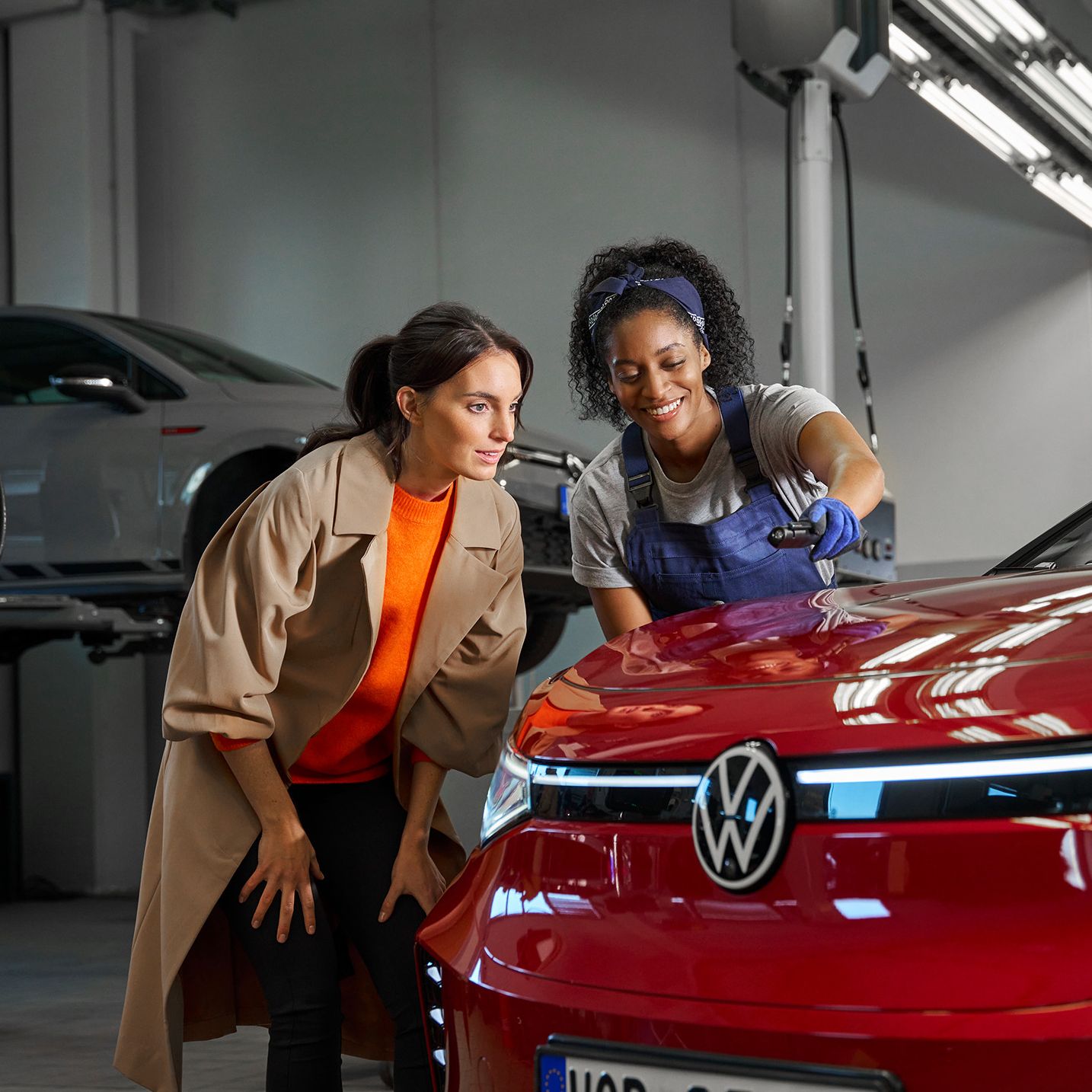 Eine Volkswagen Technikerin erklärt einer Kundin die Lackreparatur