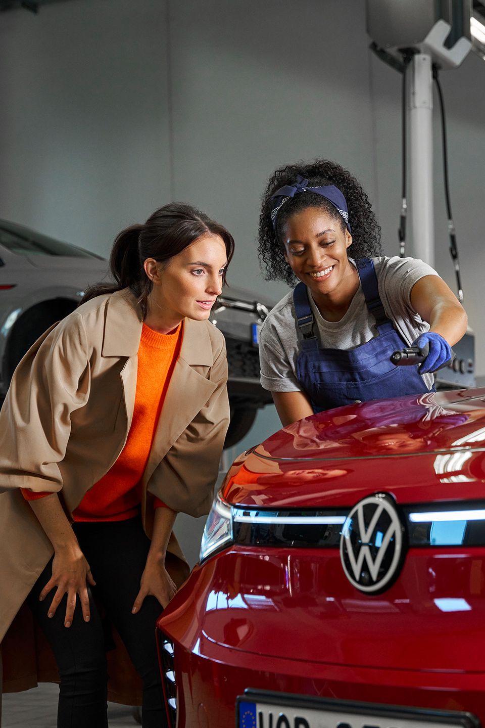 Eine Volkswagen Technikerin erklärt einer Kundin die Lackreparatur