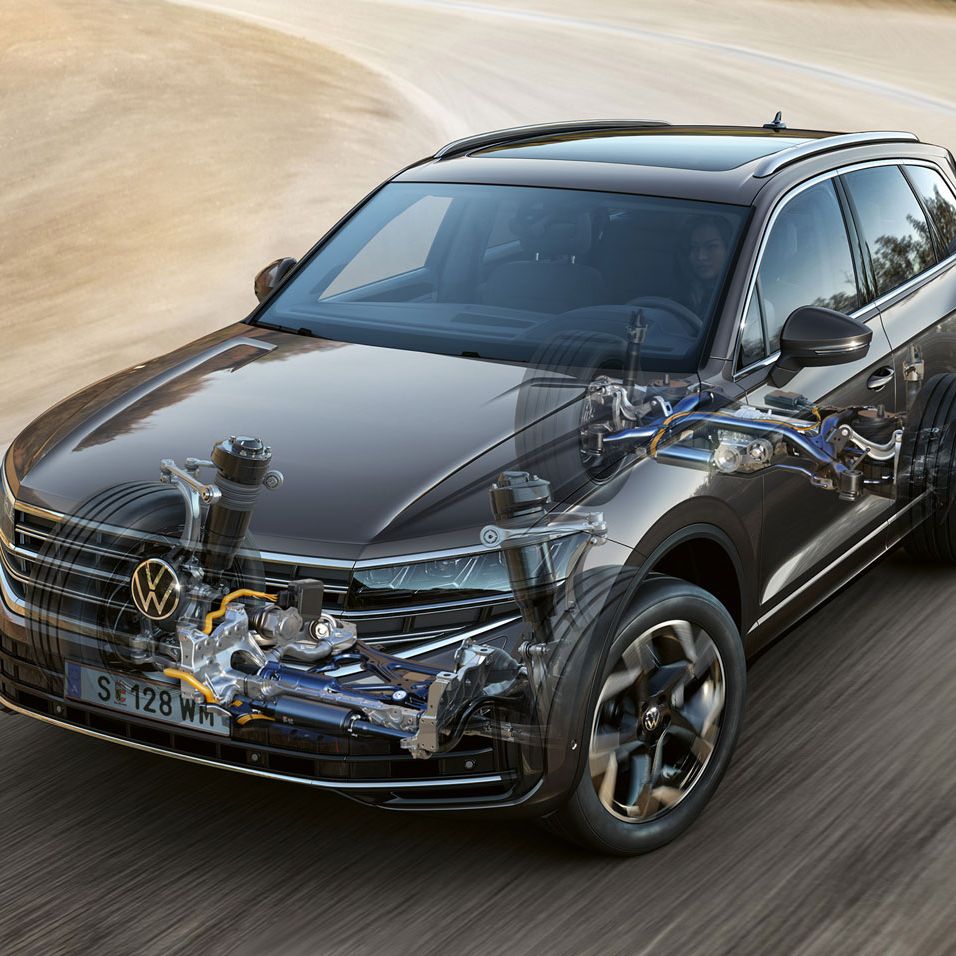 Grafik zeigt einen VW Touareg, der auf einer Straße fährt, mit transparenter Motorhaube, durch die man die Funktion der Allradlenkung erkennen kann.