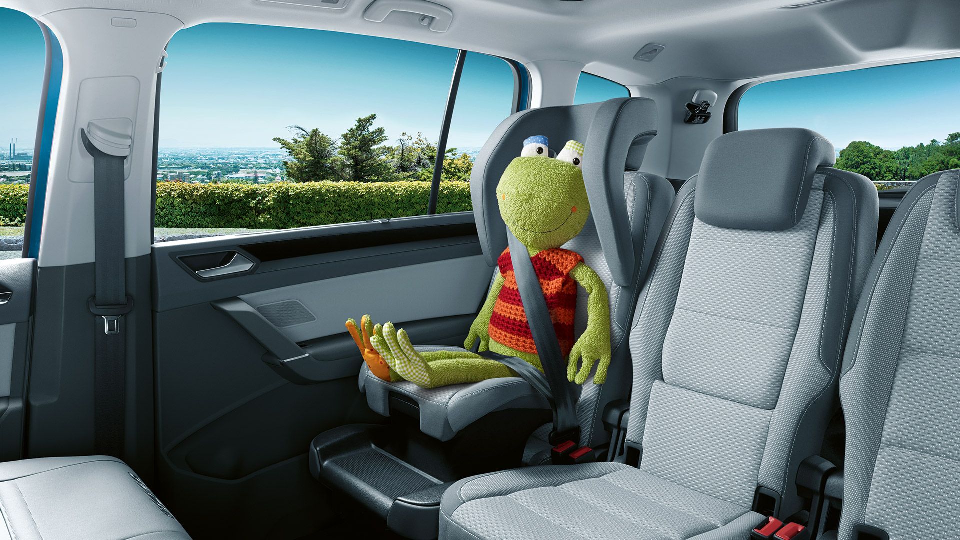 Ein Frosch-Kuscheltier sitzt auf dem integrierten Kindersitz des VW Touran. 