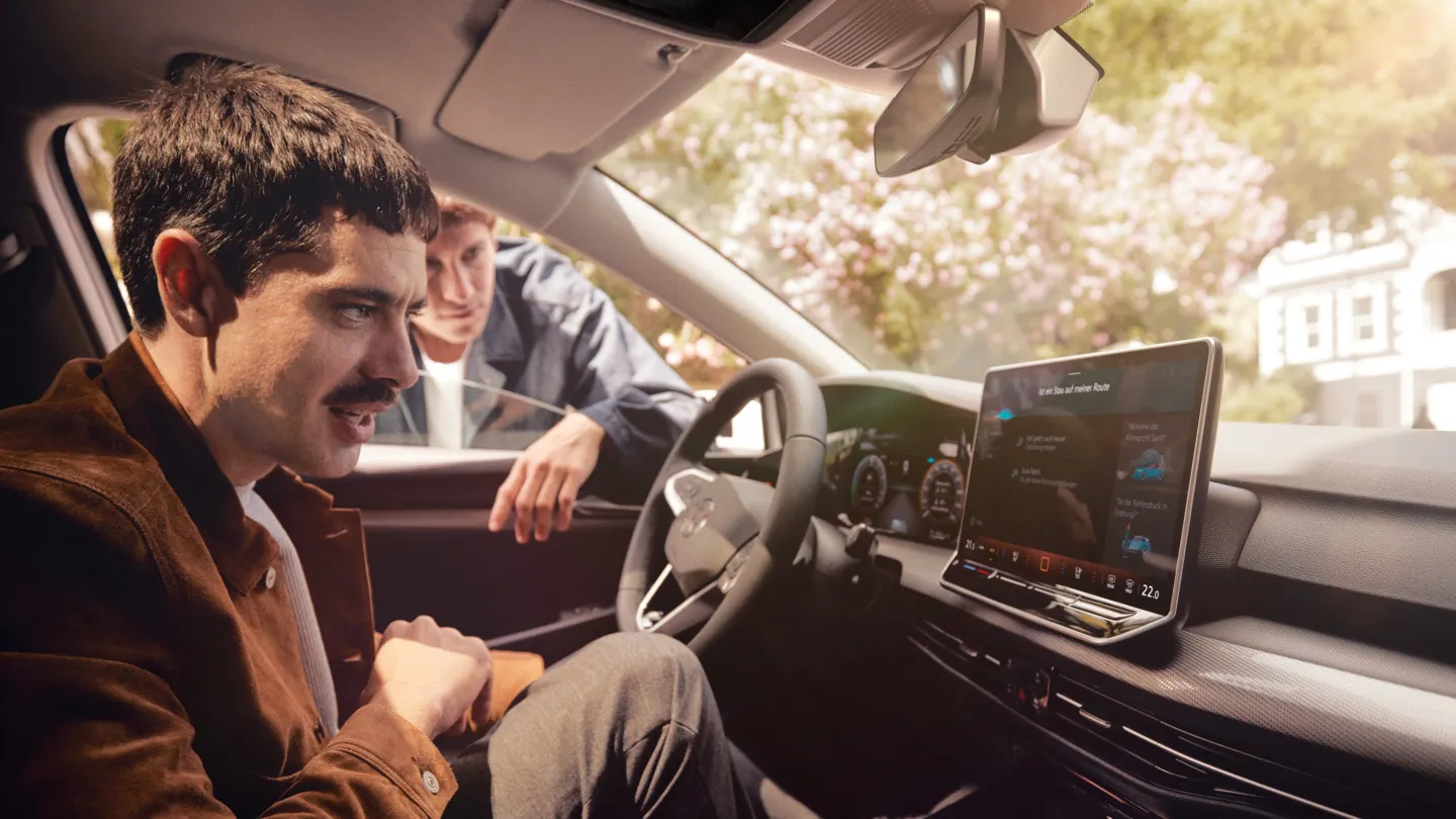 Zwei junge Männer nutzen den Sprachassistenten im VW Golf.