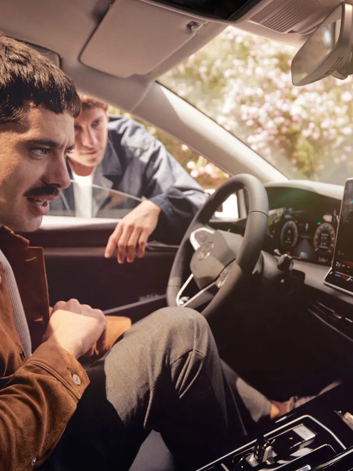 Zwei junge Männer nutzen den Sprachassistenten im VW Golf.