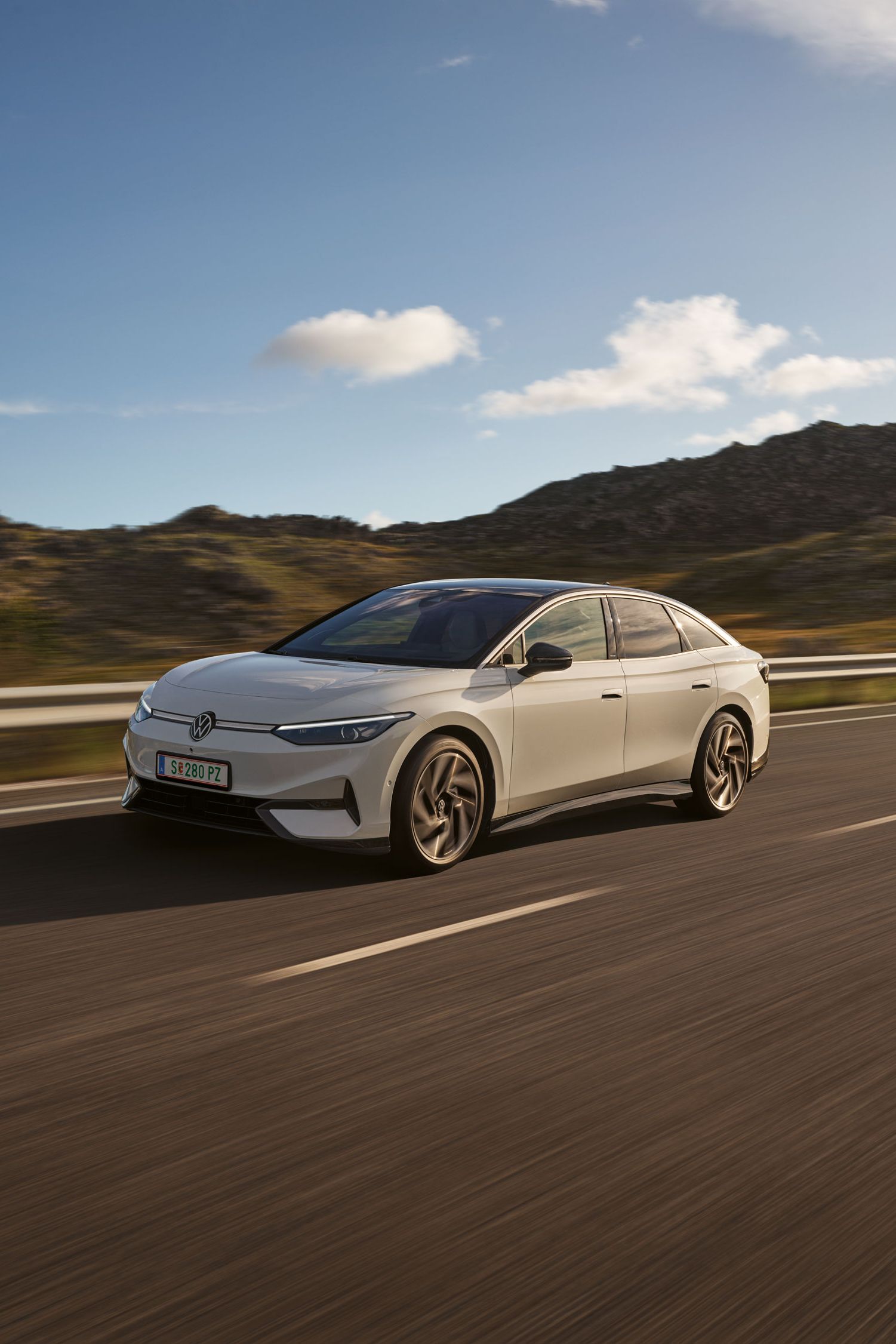 VW ID.7 fährt auf einer Landstraße, Blick auf die aerodynamisch gestaltete Front.