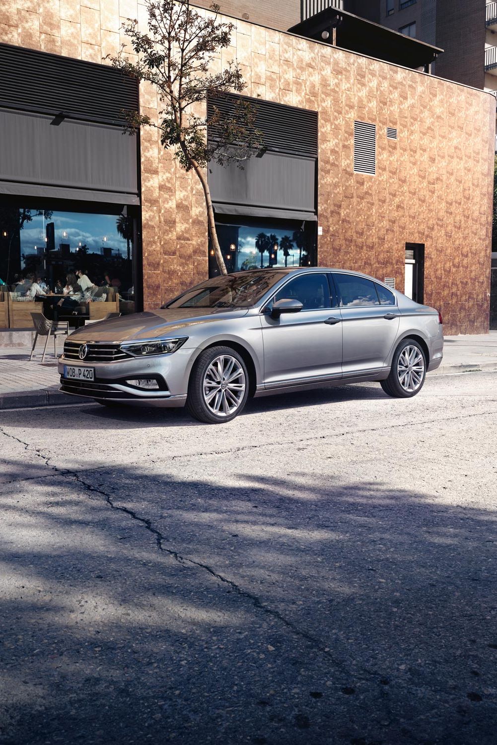 VW Passat steht auf einer Straße vor einem Café mit Sitzmöglichkeiten.