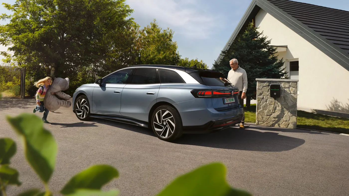 Ein VW ID.7 Tourer parkt vor einem Haus und wird am ID. Charger 2 geladen.