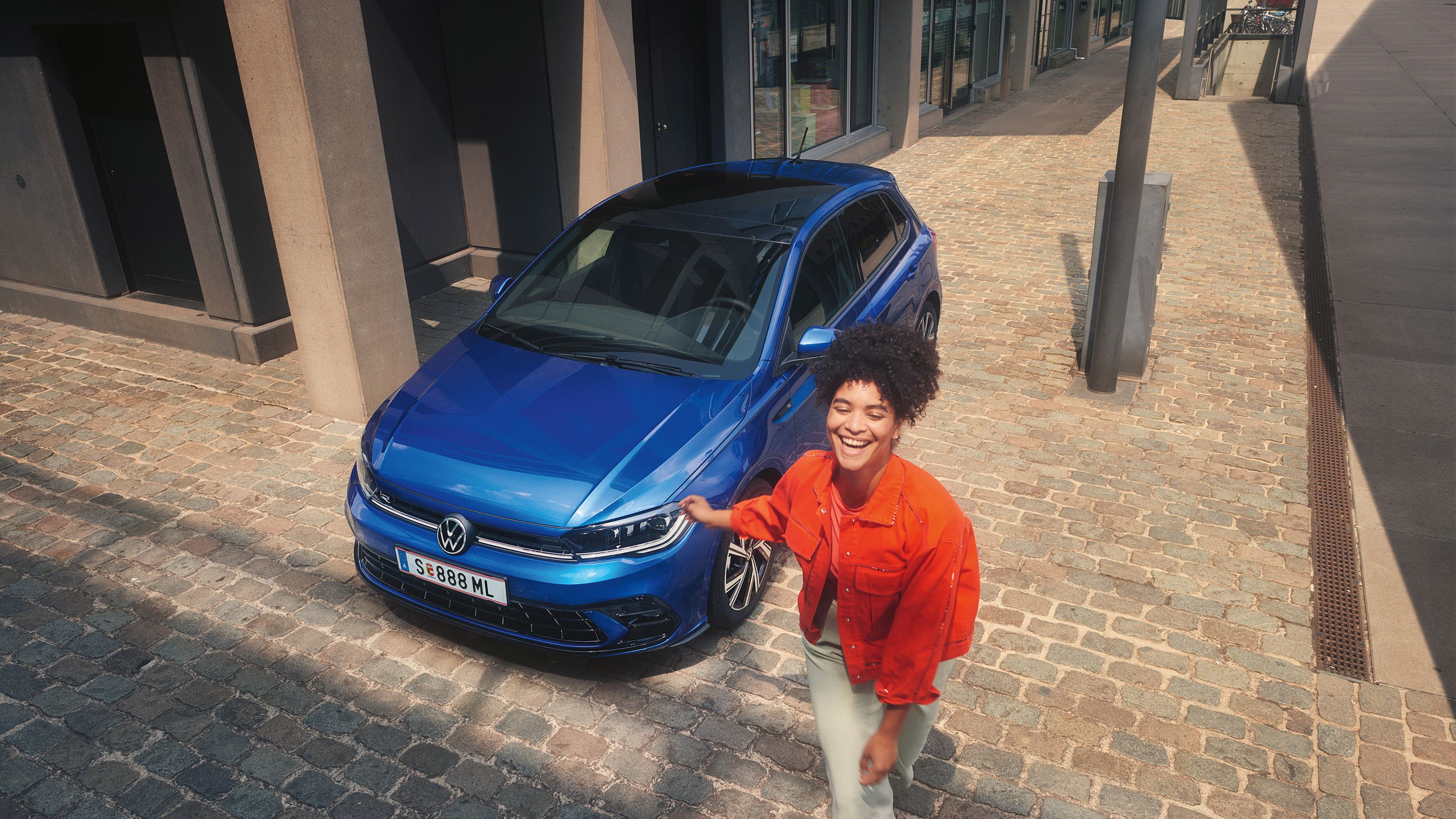 Frau geht an blauen VW Polo R-Line vorbei