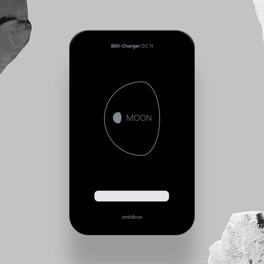 Ein BiDi-Ladegerät DC 11 mit einem eleganten schwarzen Design und dem Schriftzug "MOON" in der Mitte, umgeben von einer Kontur. Es befindet sich vor einem grauen Hintergrund mit zwei großen, strukturierten Steinen an den Seiten.