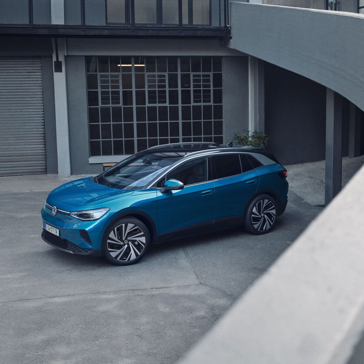 Blauer VW ID.4 parkt in einem Innenhof eines industriellen Gebäudes.