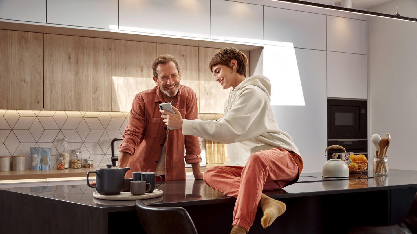 Mann und Frau schauen gemeinsam in ihrer Küche auf ein Smartphone