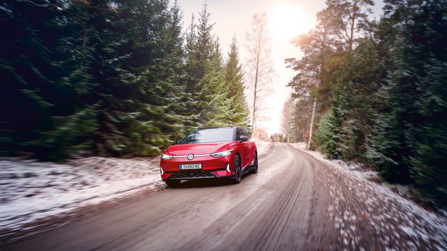 Ein roter VW ID.7 GTX Tourer fährt auf einem Waldweg, auf dem Boden liegt Schnee.