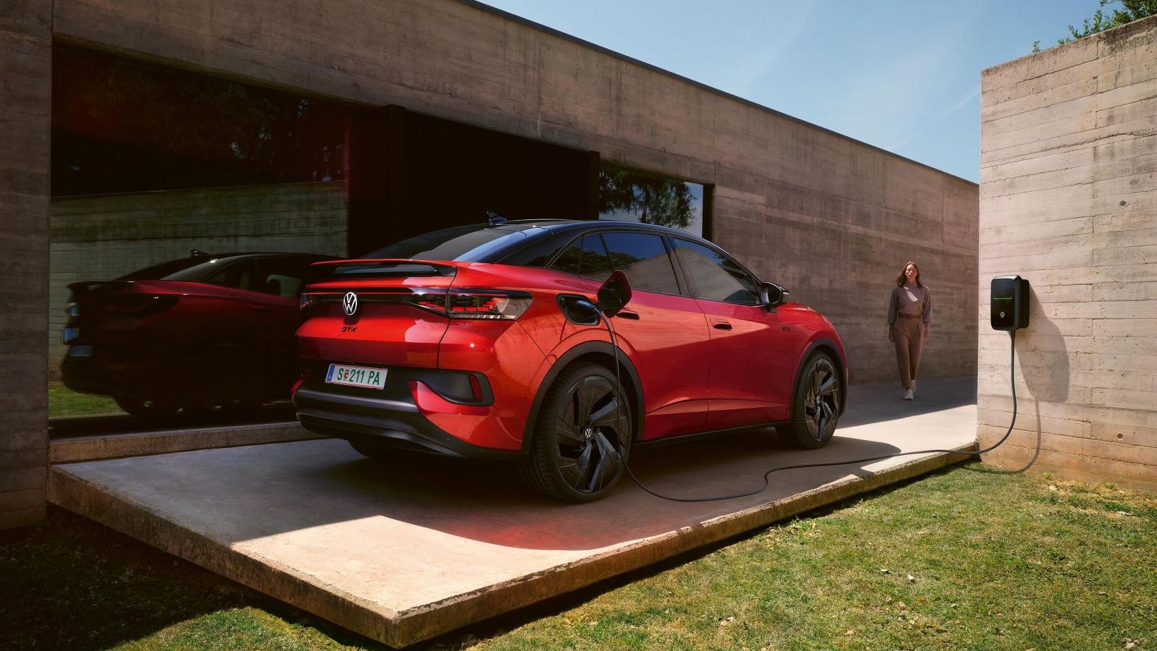Ein roter VW ID.5 GTX lädt an einer Wallbox neben einem Bungalow mit großer Glasfront.
