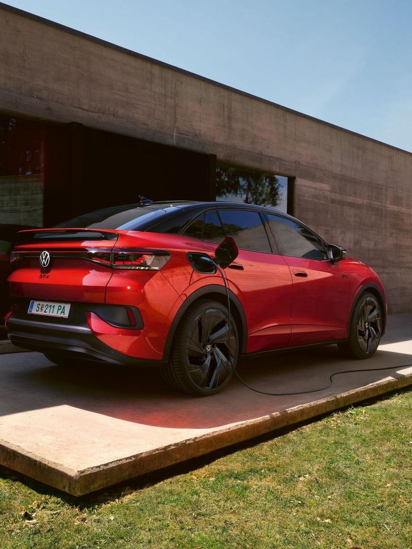 Ein roter VW ID.5 GTX lädt an einer Wallbox neben einem Bungalow mit großer Glasfront.