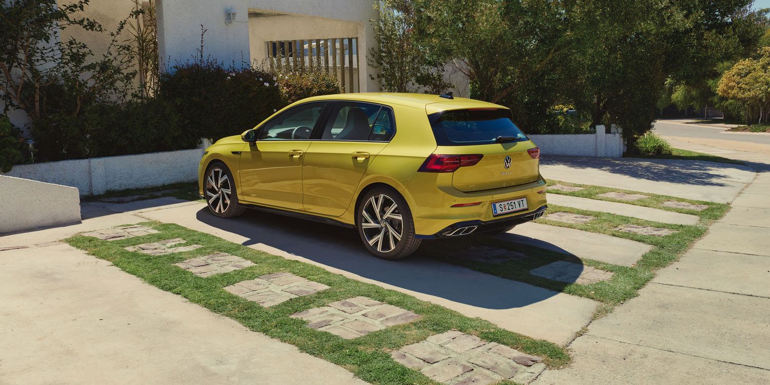 Golf 8 steht auf einem Parkplatz vor einem Haus.
