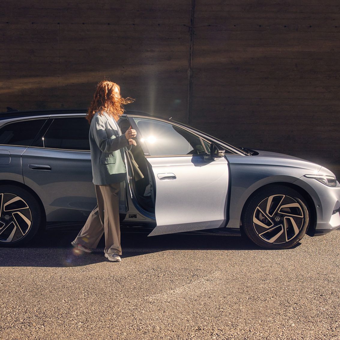 Eine Frau steht vor der geöffneten Beifahrertüre eines ID.7 Tourer 