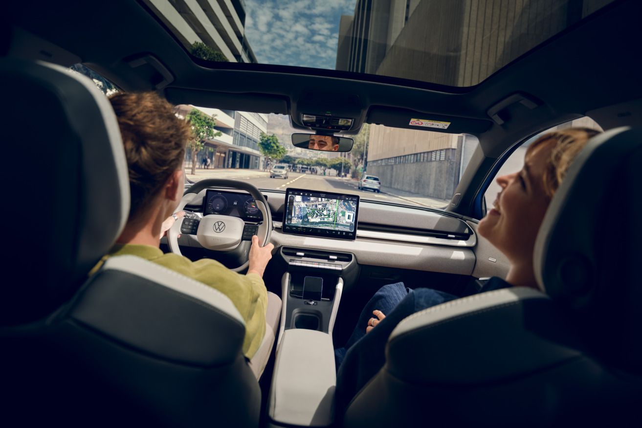 Ein Mann fährt einen VW ID. Polo Style, auf dem Beifahrersitz eine Frau die lacht. Durch das Panoramadach sind Hochhäuser zu sehen