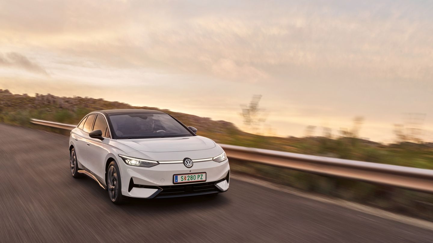 Blick auf die aerodynamisch gestaltete Front eines weißen VW ID.7, der auf einer Landstraße fährt.