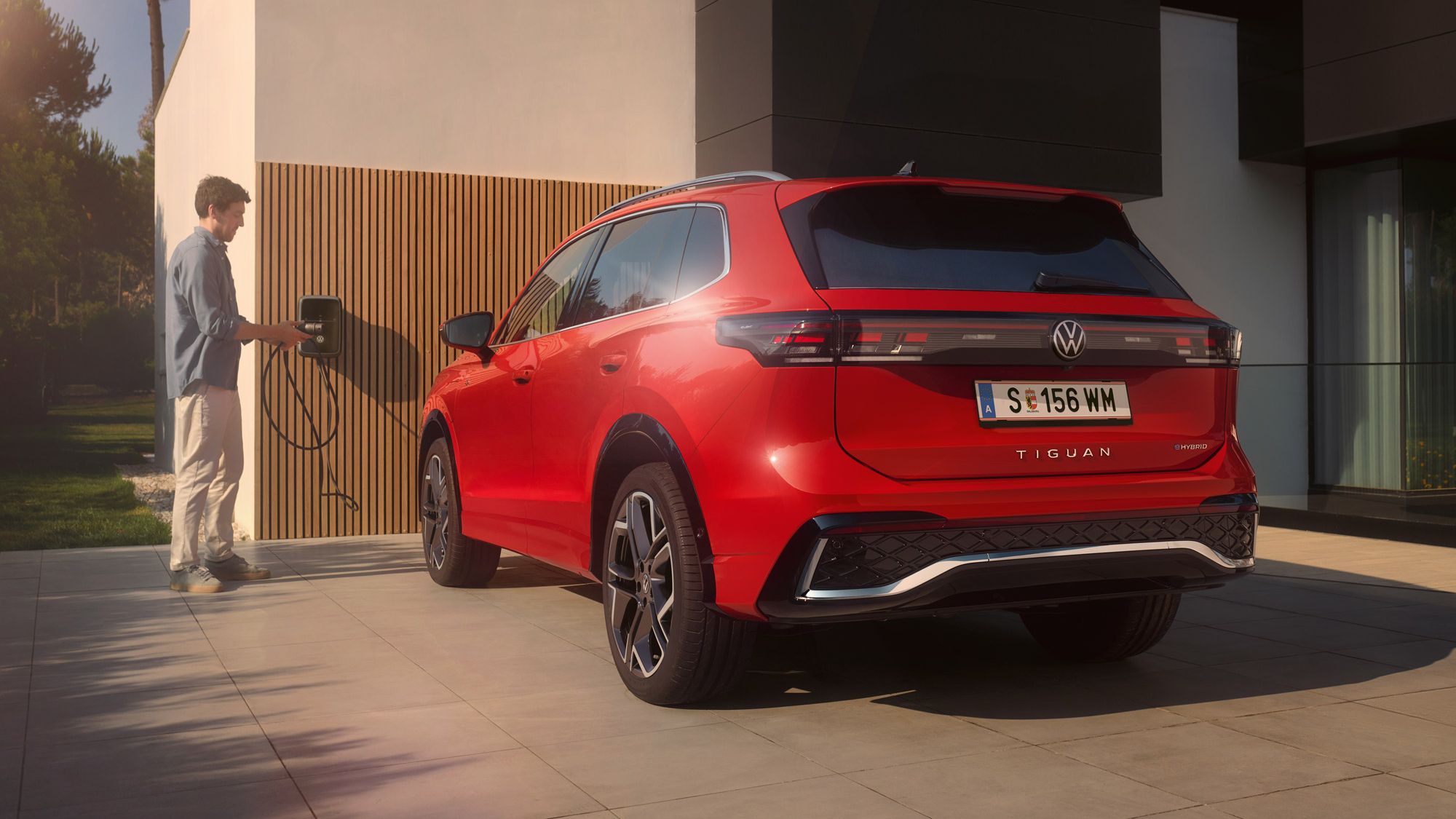 Ein Mann lädt seinen VW Tiguan R-Line eHybrid über seine Wallbox ID. Charger.