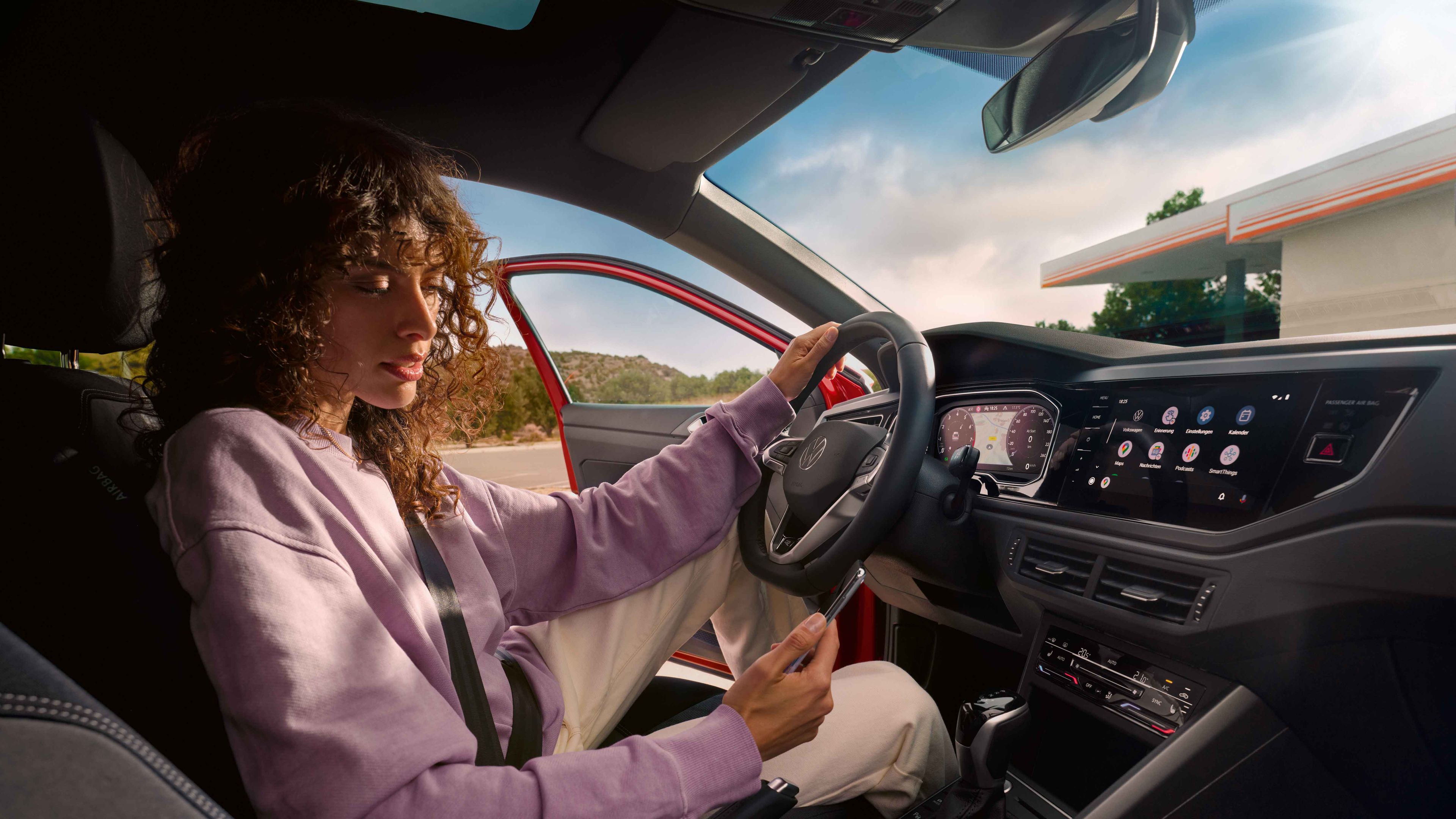 Frau sitzt in VW Taigo R-Line und blickt auf ihr Smartphone