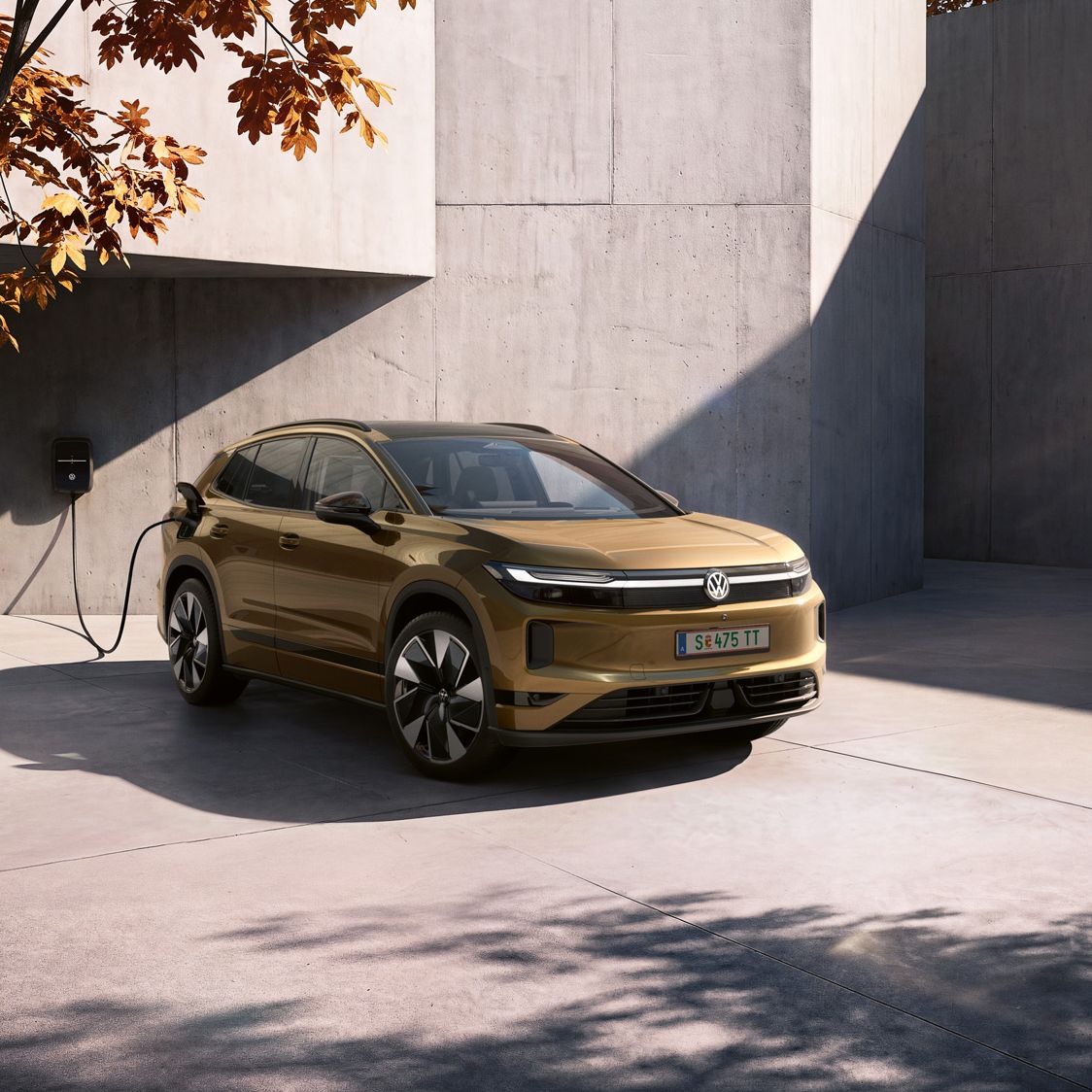 Ein Mann schaut auf das Handy in seiner Hand. Im Hintergrund lädt ein oliv-bronzefarbener VW ID.4 Reskin an einer Wallbox.