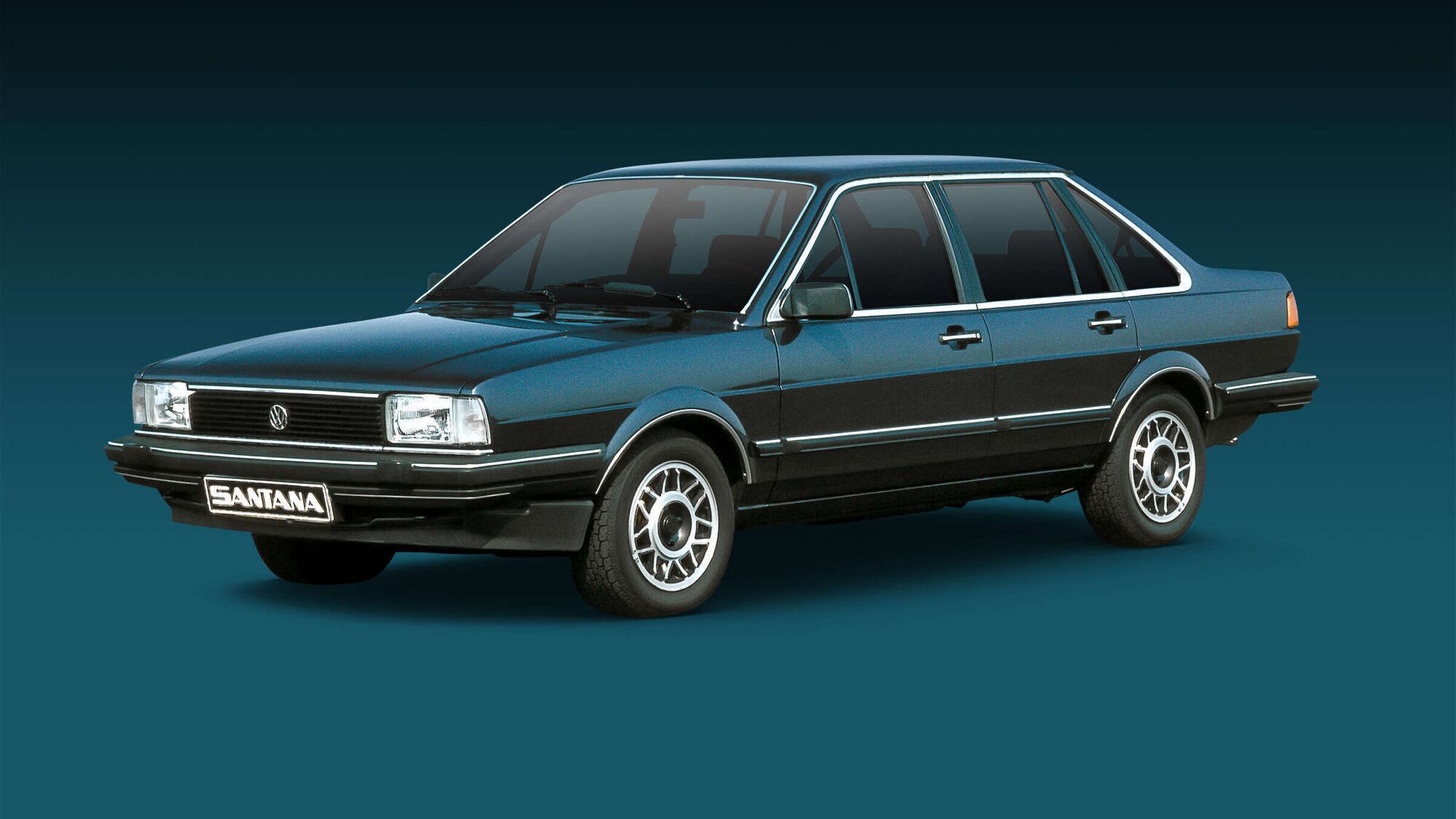Ein dunkelblauer, älterer Mittelklasse-Pkw mit Stufenheck steht vor einfarbig dunklem Hintergrund. Das Auto hat eine kantige Karosserie, Chromstoßstangen und klassische Leichtmetallfelgen. Vorne ist ein Nummernschild mit der Aufschrift „Santana“ zu sehen.