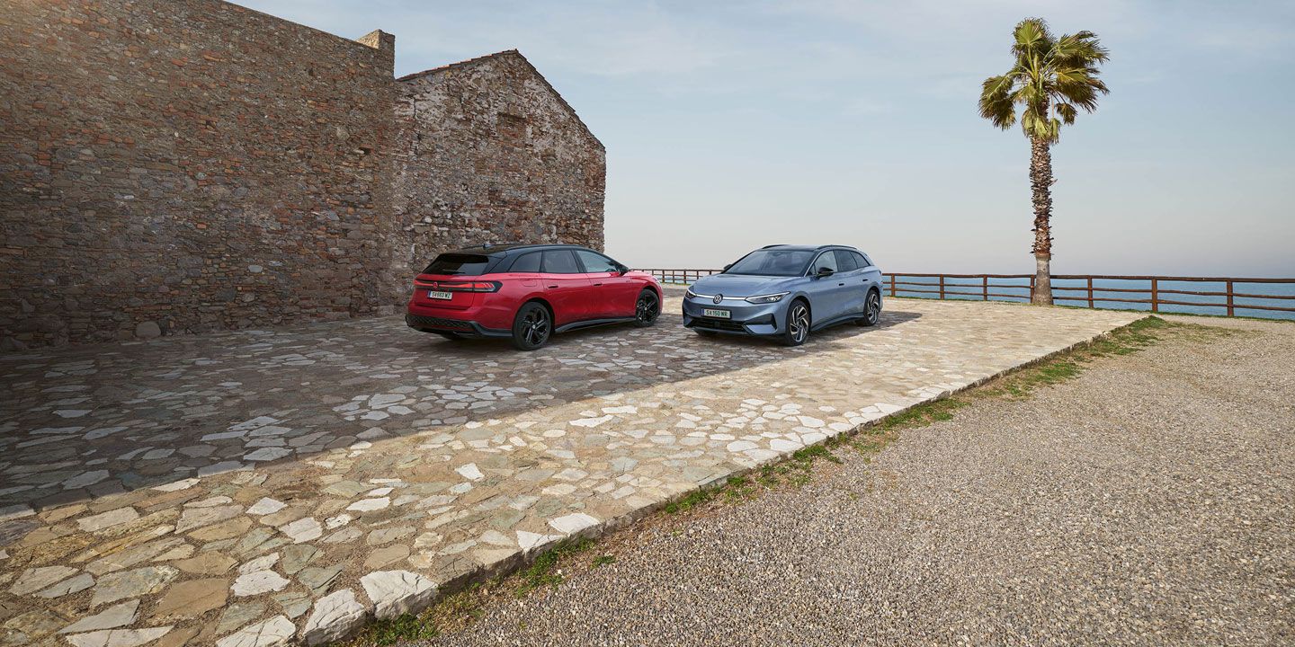 Ein roter VW ID.7 GTX Tourer und ein blauer VW ID.7 Tourer stehen auf einer Parkfläche am Meer.