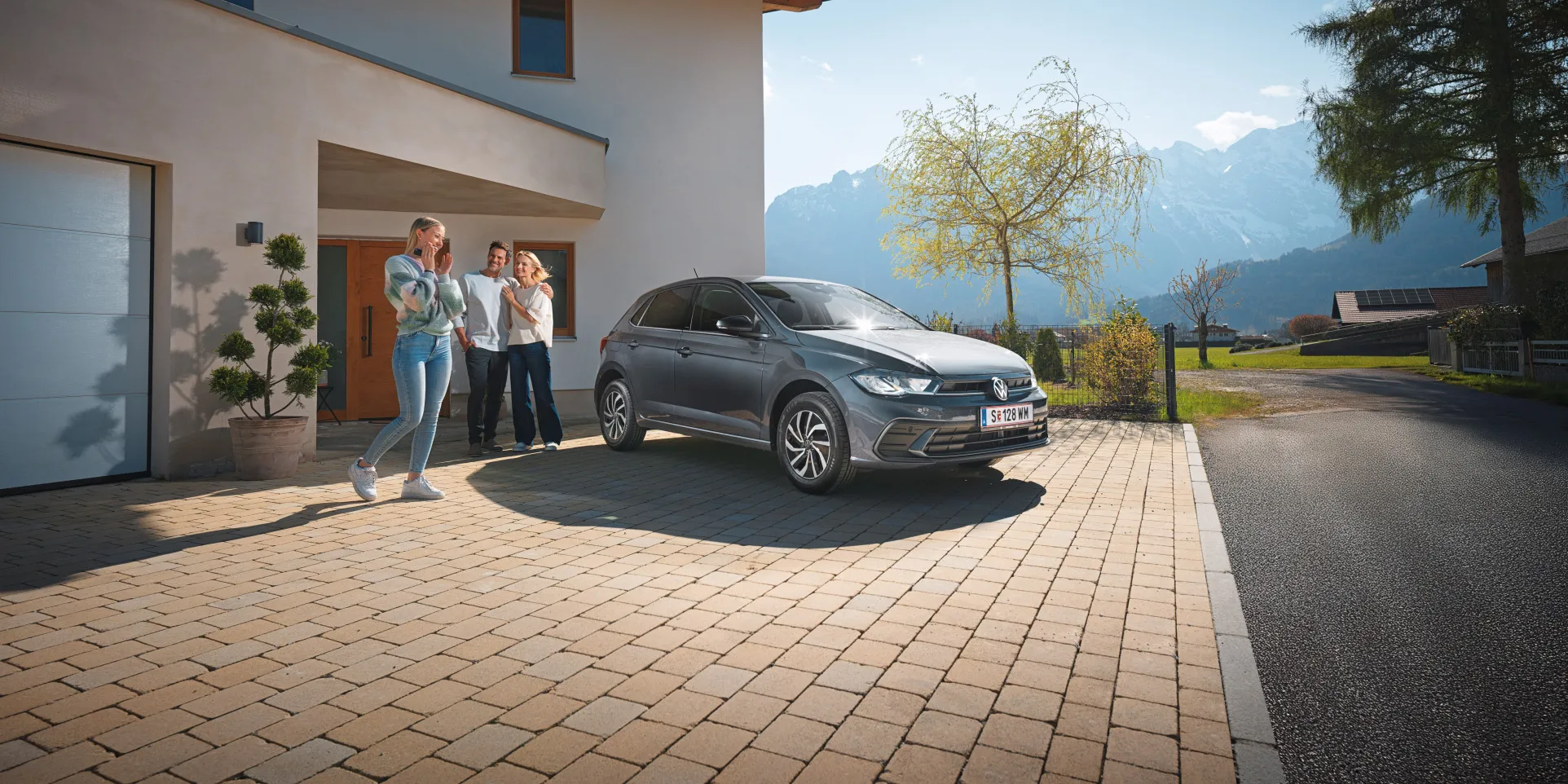 Polo steht geparkt vor einem Haus mit einer Familie im Hintergrund.