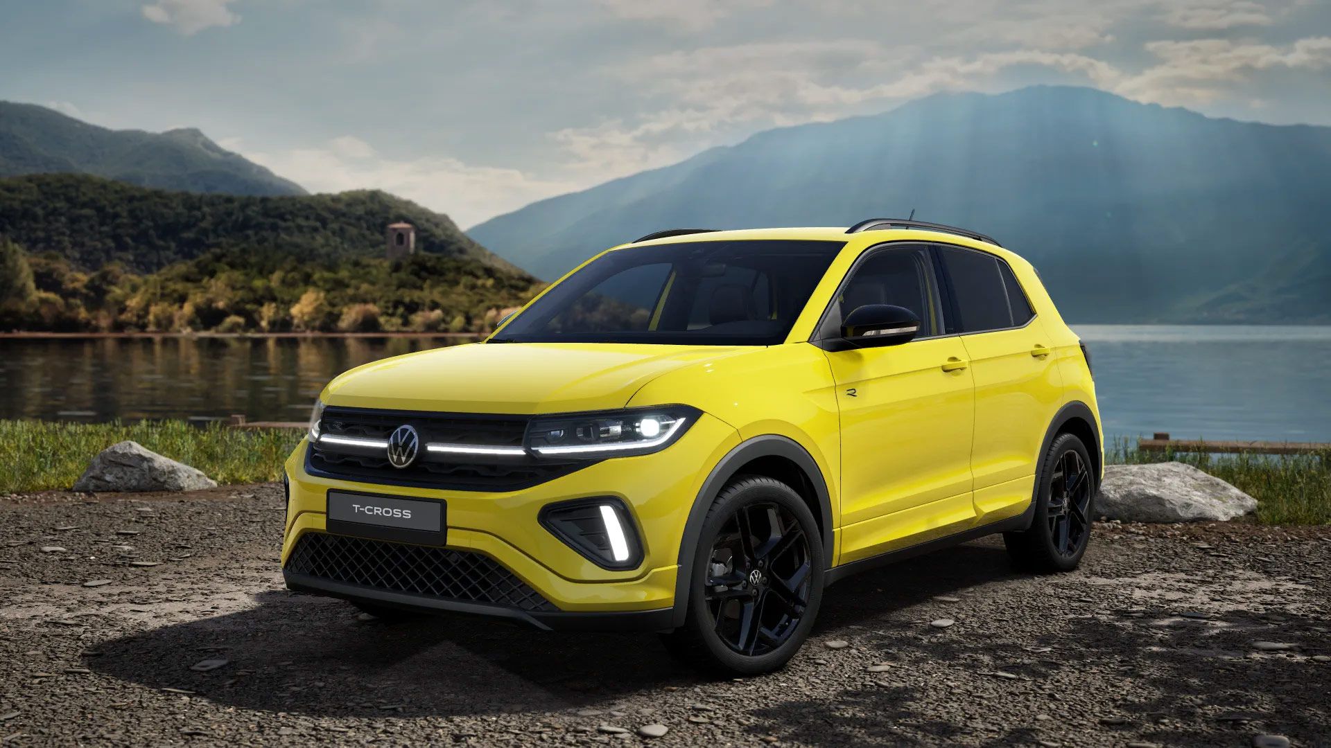 Ein gelber Volkswagen T-Cross steht vor einer malerischen Landschaft mit einem See und Bergen im Hintergrund. Das Auto hat moderne Scheinwerfer und dunkle Felgen. Sonnenstrahlen brechen durch die Wolken und erleuchten die Szene.